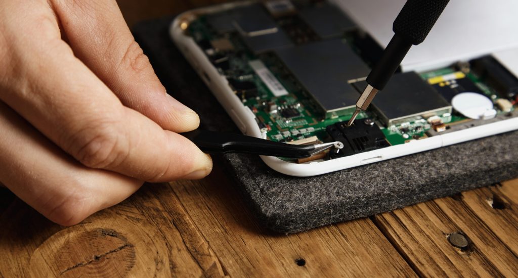 Master uses special tools to disassemble electronic device carefully Pincers and bit screw driver closeup